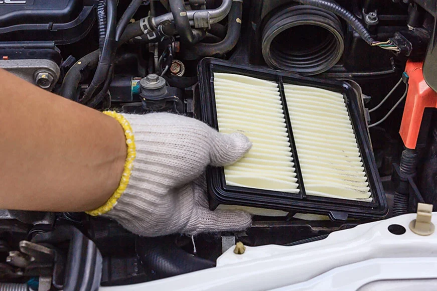 GMC Maintenance Professional is putting in a new air filter to an SUV engine with his white-gloved hand