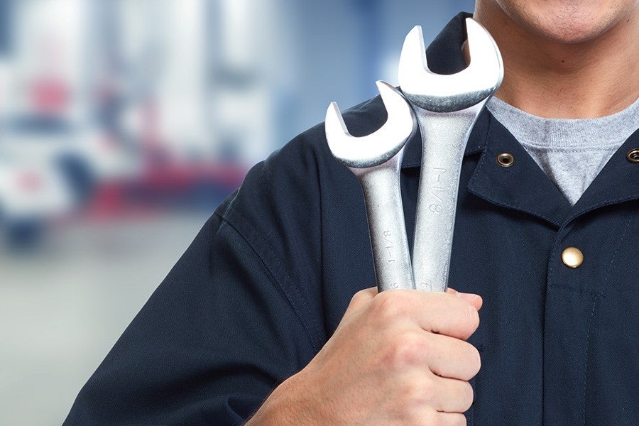 mechanic holds wrenches in hand